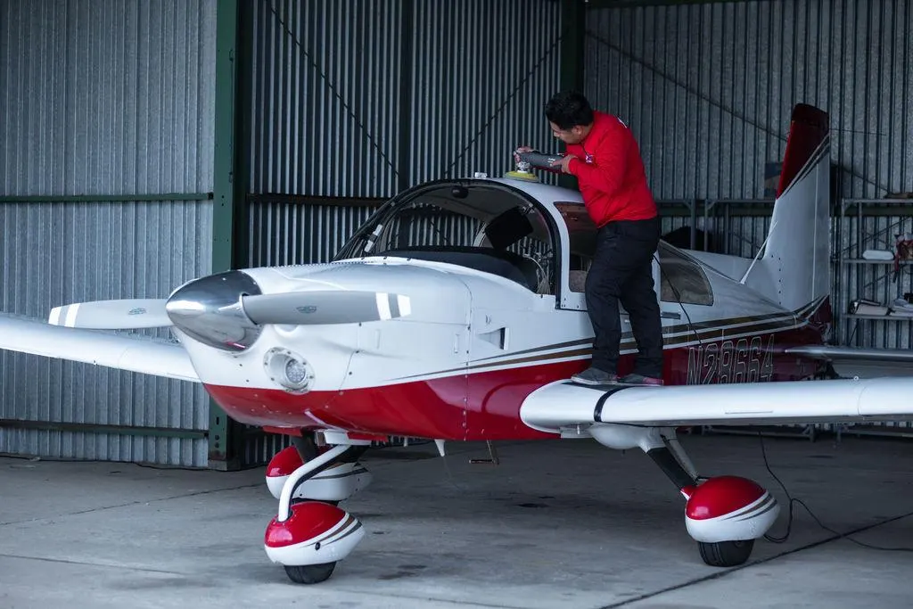 Fast Clean technician detailing a small propeller aircraft inside a hangar.