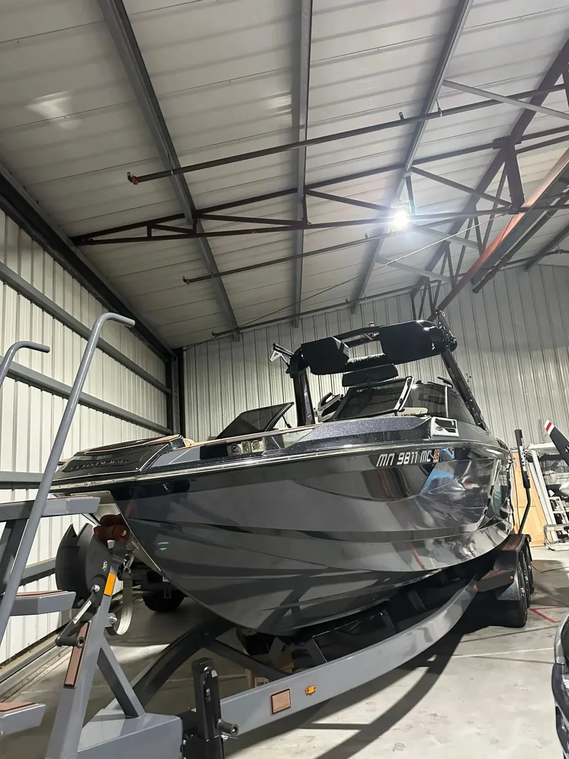 Detailed dark wakeboard boat on a trailer inside a storage facility after mobile marine detailing.