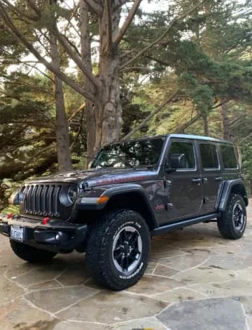 Dark gray Jeep Wrangler Rubicon parked on a flagstone driveway surrounded by trees in Santa Cruz County.