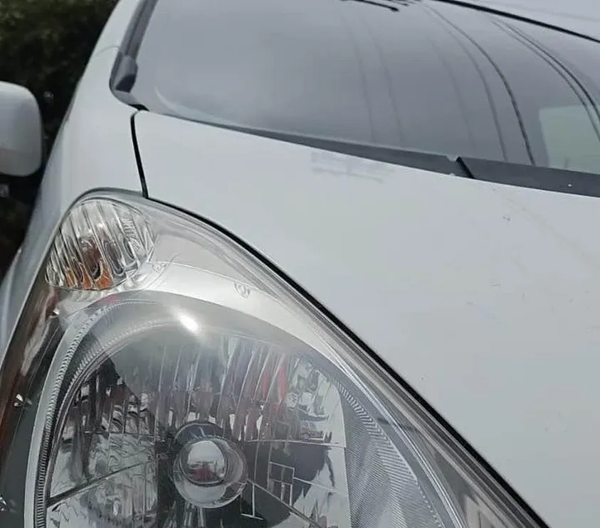 Close-up of a clear, restored vehicle headlight and hood after detailing by Fast Clean Mobile Detailing.